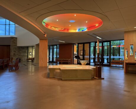 Church narthex with circular baptismal stained glass ceiling installation, contemporary glass design shaping entry experience
