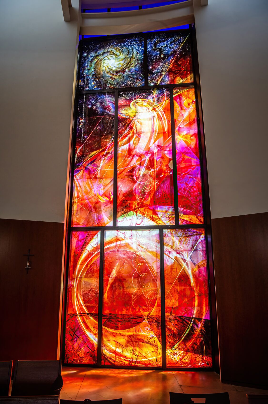 Contemporary stained glass Marian window for new church construction, depicting Mary as woman clothed in the sun with cosmic movement and light