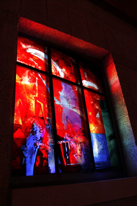 Vertical stained glass window with flowing color and light, architectural glass commission shaping sacred space